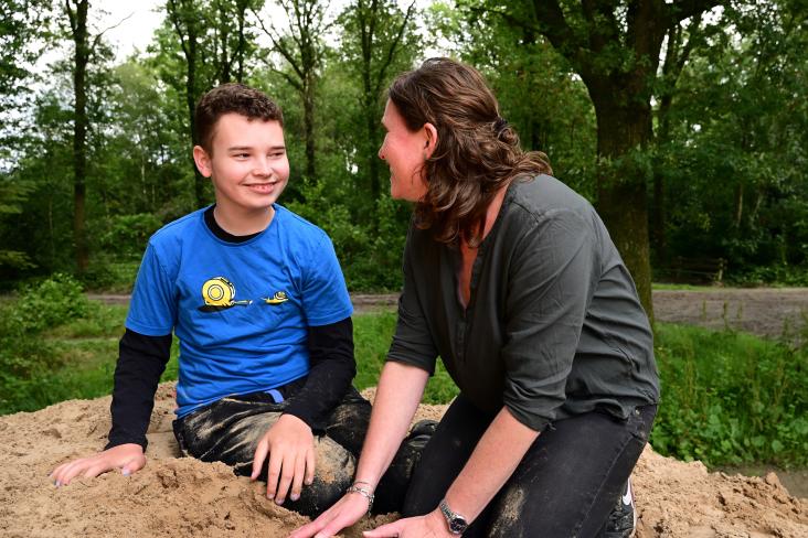Jongen met beperking met moeder spelen in zand