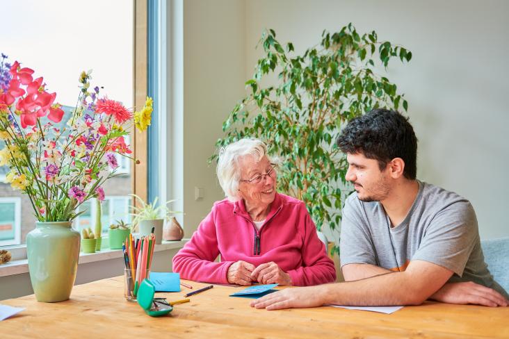 Oudere vrouw met vrijwilliger zitten aan tafel