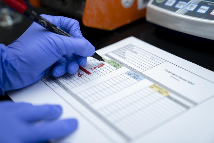 Handen met medische handschoenen aan die iets opschrijven