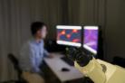 Man achter computerschermen met microscoop ervoor