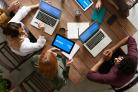 Groep mensen van bovenaf gefotografeerd, werken aan een tafel op laptops