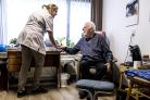 zorgprofessional met oudere man in huiskamersetting