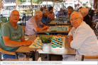 Een groep oudere mensen zit op een terras en spelen damspelletjes.