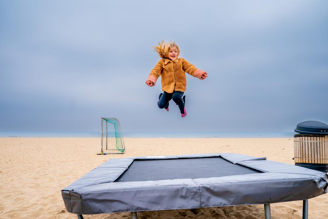 Jongen op trampoline op het strand