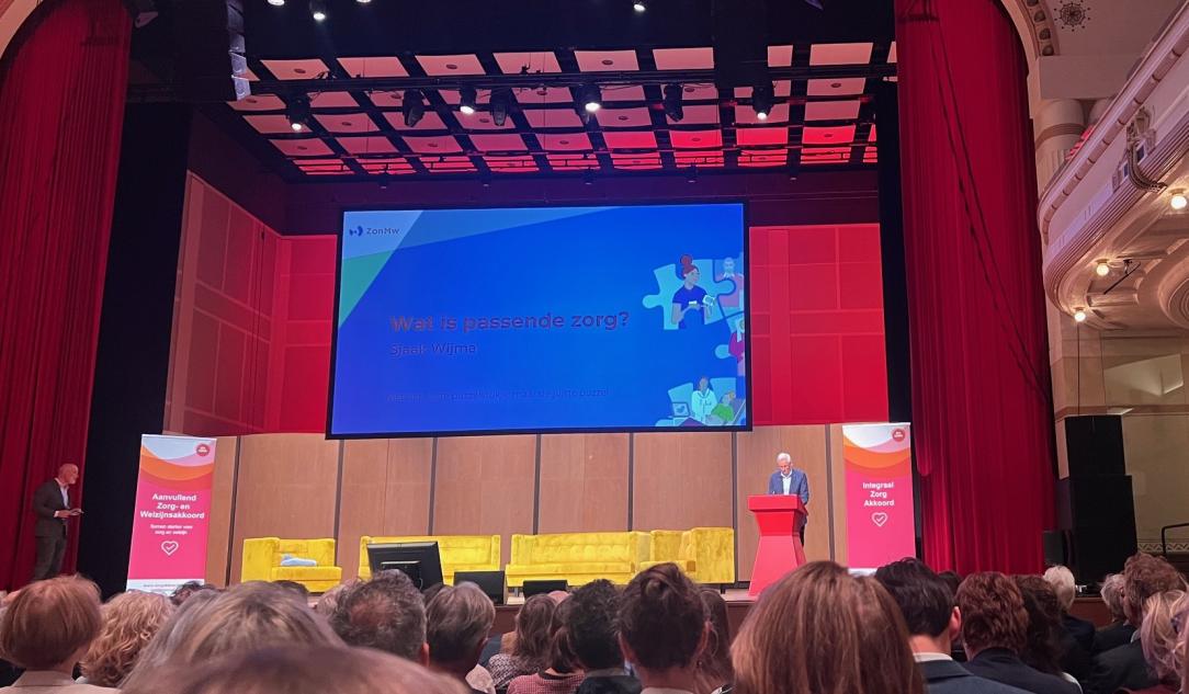 Grote zaal met man achter spreekgestoelte