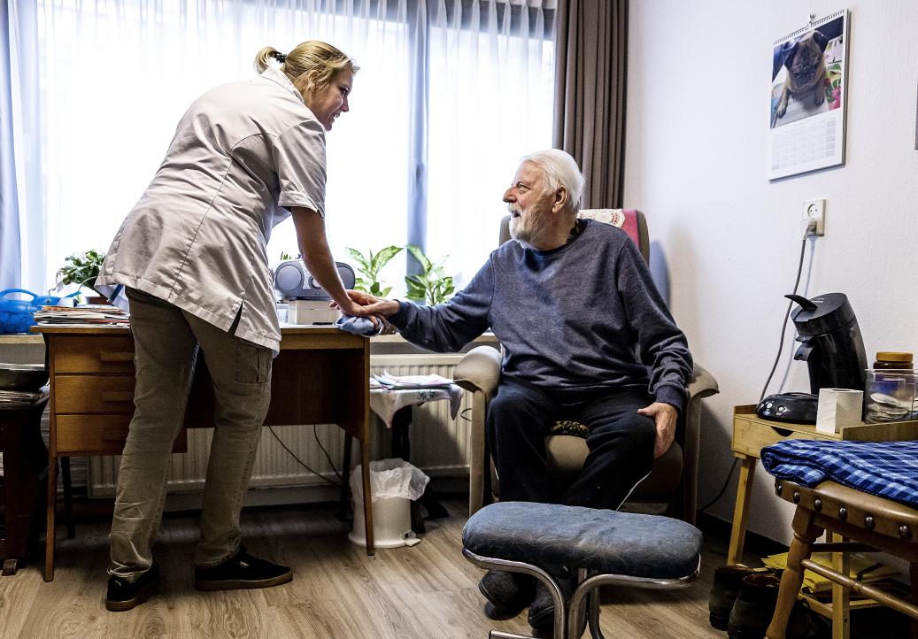 zorgprofessional met oudere man in huiskamersetting
