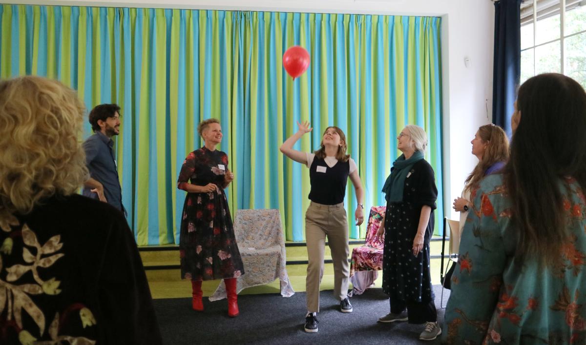 Mensen in een kring die samen een ballon in de lucht houden
