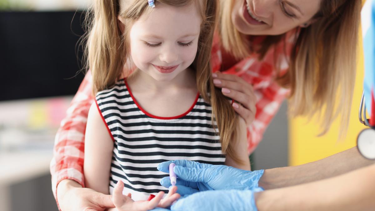 Meisje krijgt een prik in haar vinger door medicus