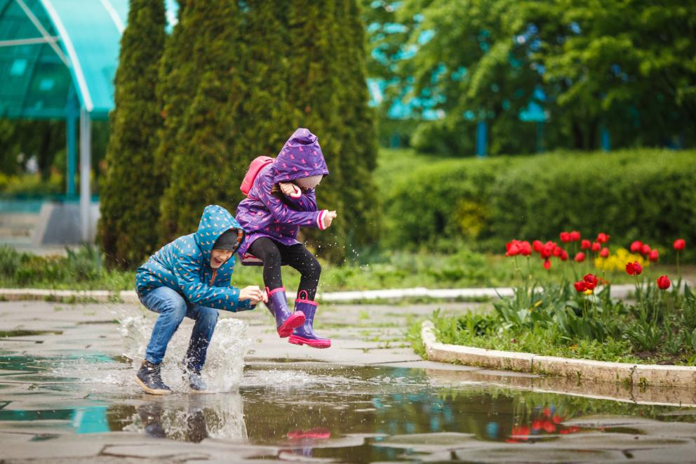 Twee kinderen springen in een plas water